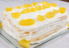 Bolo de Ananás caseiro da Avó Palmira, muito fofo e húmido, coberto com creme branco e pedaços de ananás, servido numa travessa de vidro, perfeito para sobremesas e lanches em família.