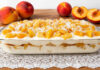 Sobremesa de pêssego com bolacha Maria e coco servida numa travessa de vidro, com camadas cremosas, pedaços de pêssego fresco e coco ralado, perfeita para os dias quentes e almoços em família.